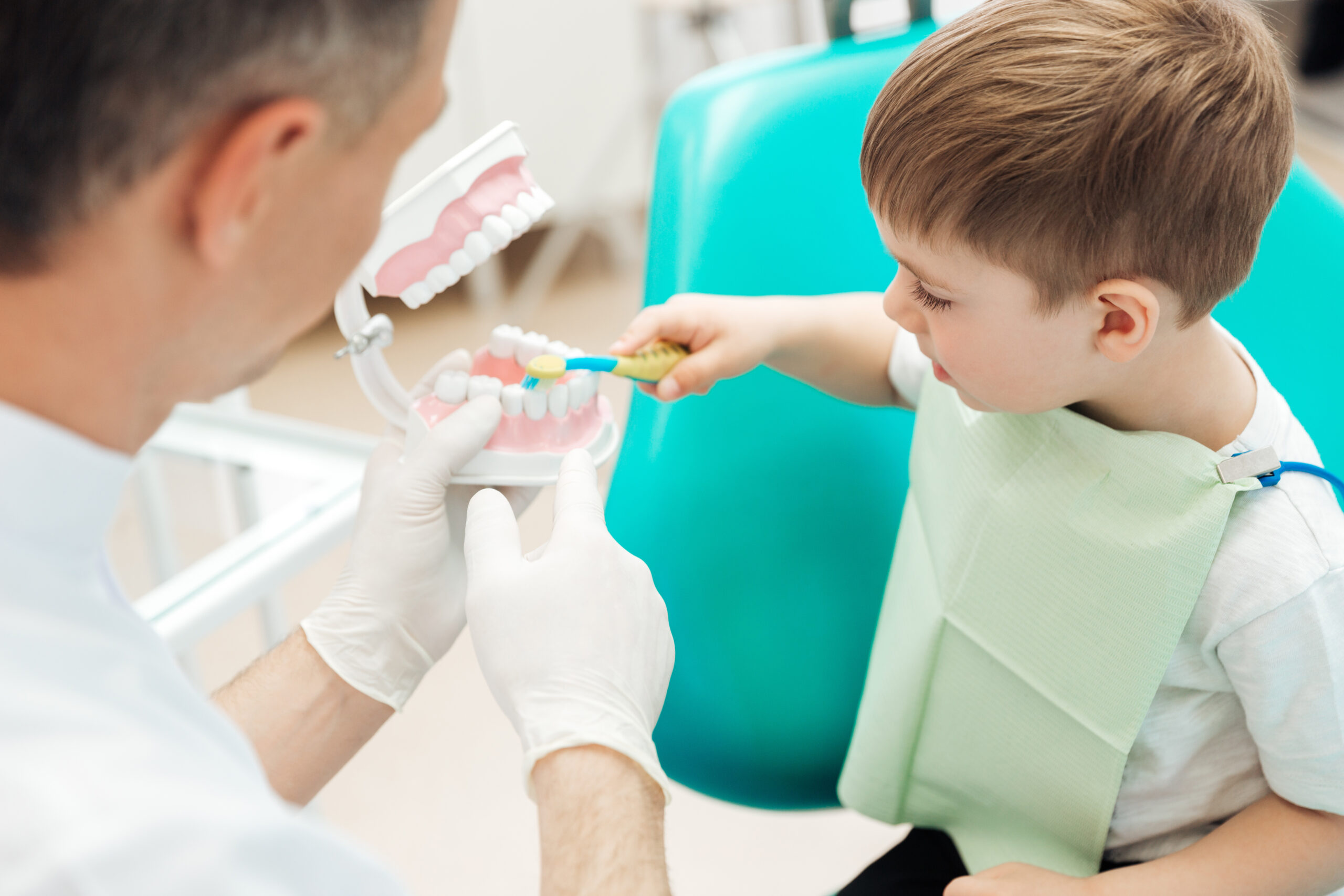 Dentist teaching little boy bruching teeth in dental clinic - Kembla St Dental